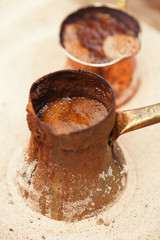 coffee preparation in copper pot with hot golden sand outdoor