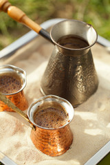 coffee preparation in copper pot with hot golden sand outdoor