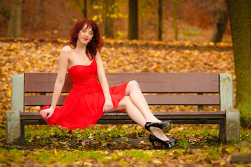 woman red dress sitting on bench in autumn park