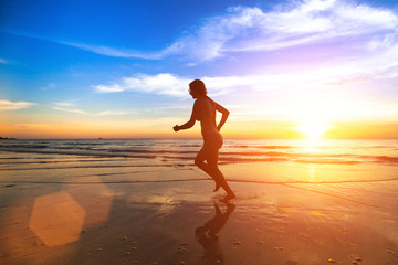 Young runner woman, jogging along the sea beach.