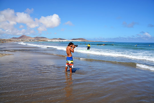 hombre fotografiando en la playa de famara de lanzarote