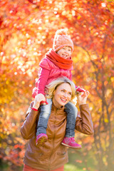 Happy mother and and smiling kid walking together outdoor in aut