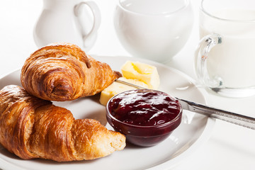 Fresh croissants with butter and a glass of milk