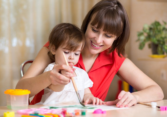 cute mother teach her daughter kid to paint