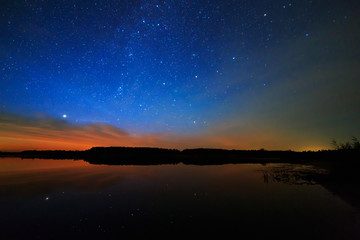 Fototapeta na wymiar Morning dawn on a starry background sky reflected in the water o