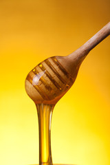 Close-up shot of wooden drizzler with flowing honey