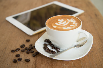 cup of coffee on table in cafe with tablet