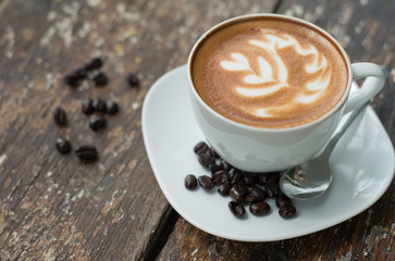 Hot latte in white cup on wood background
