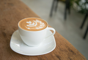 Hot latte in white cup on wood background