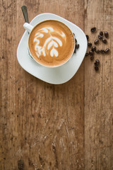 Hot latte in white cup on wood background