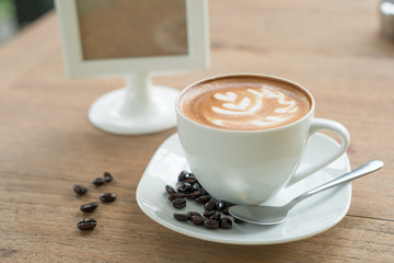 Hot latte in white cup on wood background