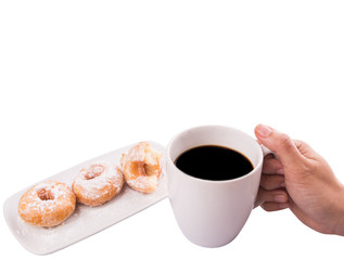 Female hand holding a mug of coffee with homemade doughnuts