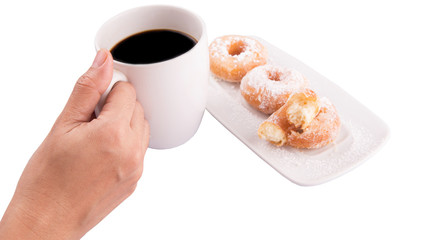 Female hand holding a mug of coffee with homemade doughnuts