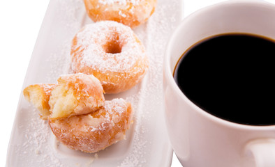 A mug of coffee and homemade doughnut with sugar toppings 