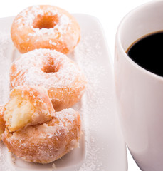 A mug of coffee and homemade doughnut with sugar toppings 