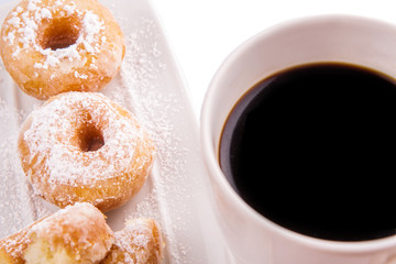 A mug of coffee and homemade doughnut with sugar toppings 
