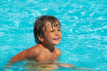 Smiling boy swimming in pool and looking