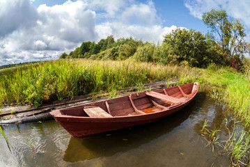 Naklejka na ściany i meble Old wooden boat at the lake in summer day