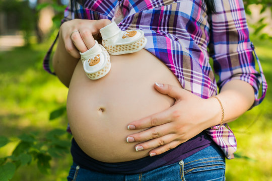 Pregnant Woman Holding Baby Shoes