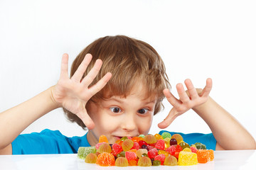 Little boy with colored jelly candies on a white background