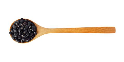 Black beans with wooden spoon isolated on white.