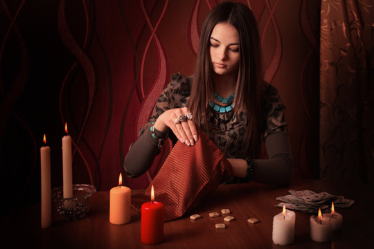 Young woman with runes and divination cards in room