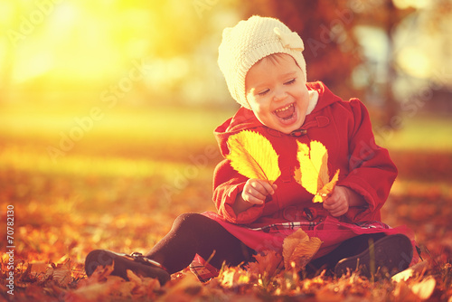 happy little child, baby girl laughing and playing in autumn