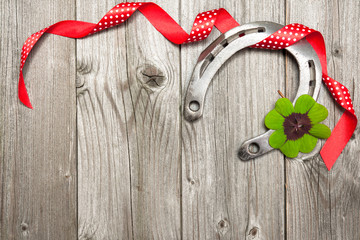 Horseshoe, shamrock and red ribbon on old wooden