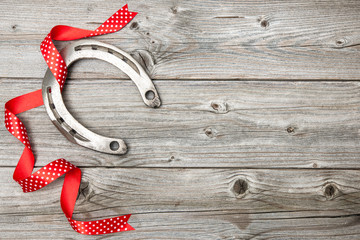 Horseshoe with red ribbon on old wooden