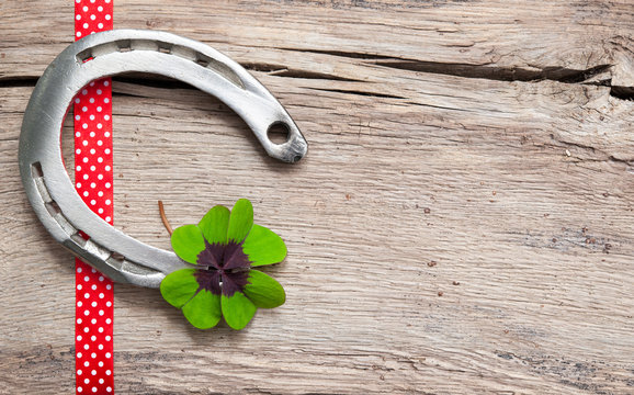 Horseshoe, shamrock and red ribbon on old wooden