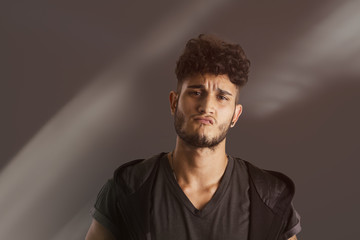 Handsome young man in dark t-shirt on black background