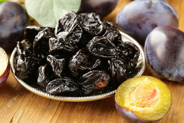 Dried plums prunes and fresh berries on the wooden table