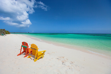 Fototapeta na wymiar Colorful adirondack lounge chairs at Caribbean beach
