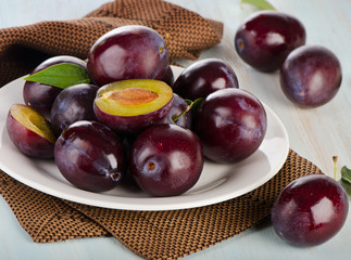 Ripe plums on  white plate