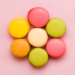 Sweet colorful macaroons against pink background. Top view