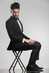 elegant man in tuxedo sitting on a stool