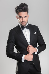 young man ajusting his tuxedo while looking at the camera