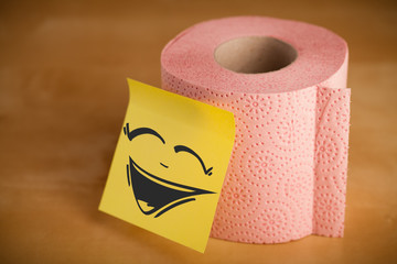 Post-it note with smiley face sticked on toilet paper