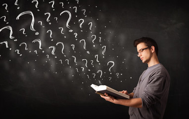 Young man reading a book with question marks coming out from it