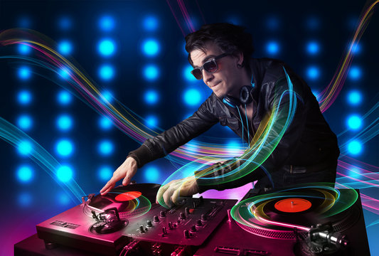 Young Dj mixing records with colorful lights