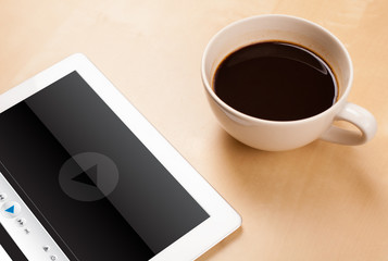 Fototapeta na wymiar Tablet pc showing media player on screen with a cup of coffee on