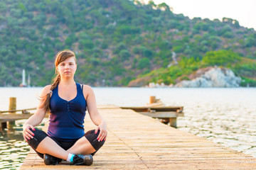 portrait of a girl in a lotus position on the pier