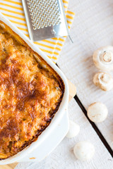 meat lasagna with mushrooms in a white bowl on a blackboard