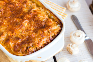 meat lasagna with mushrooms in a white bowl on a blackboard