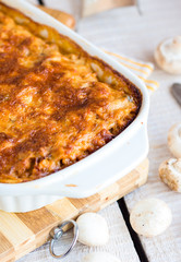 meat lasagna with mushrooms in a white bowl on a blackboard