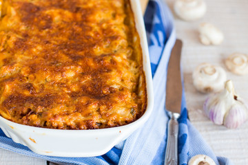 meat lasagna with mushrooms in a white bowl on a blackboard
