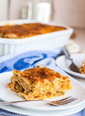 eating a piece of meat lasagna with mushrooms, blue towel