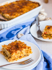 eating a piece of meat lasagna with mushrooms, blue towel