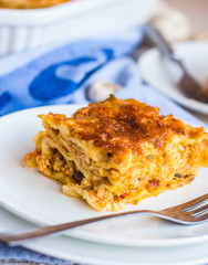 piece of meat lasagna with mushrooms, cutlery, .Italian food