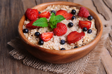 Tasty oatmeal with berries on table close-up